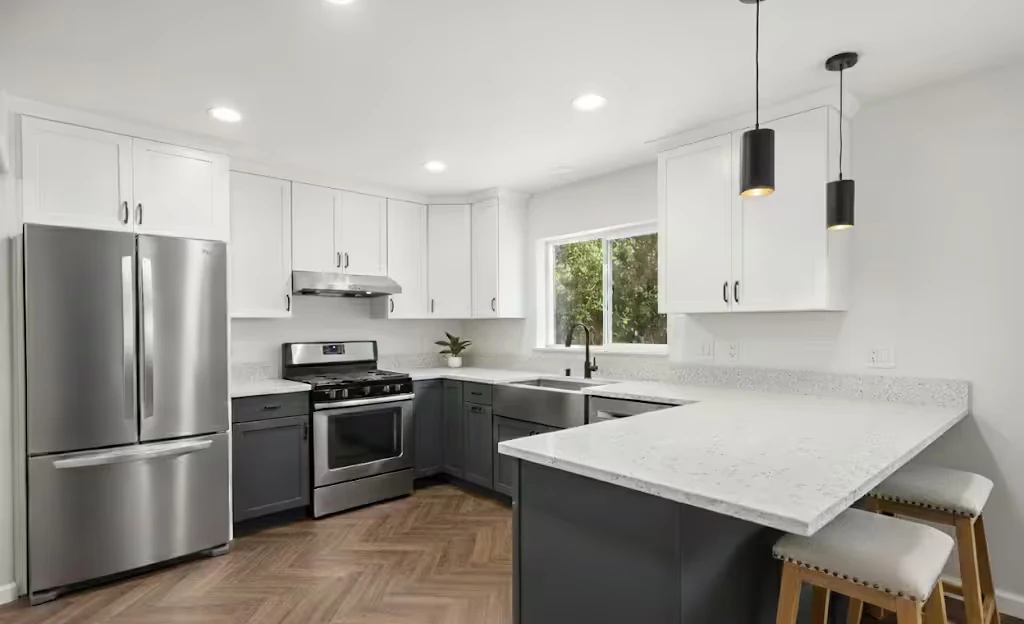 Modern kitchen with gray cabinets, white countertops, large island, and stainless steel appliances.