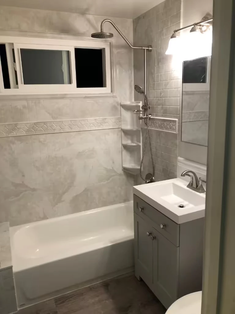 Modern bathroom with gray tiled bathtub and shower, vanity with sink, and premium finishes.