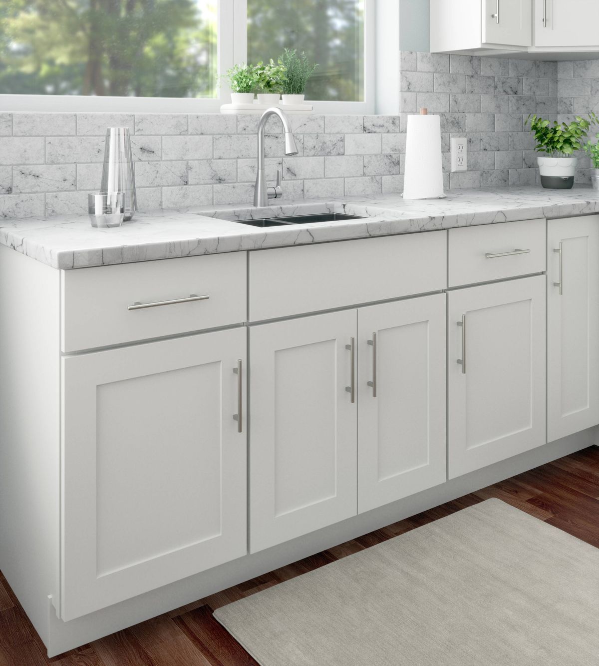 Modern small kitchen with gray cabinets, stainless steel appliances, and white countertops.